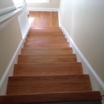 View from the top of wood stairs and landing to be refinished by sanding and staining