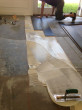 Dan's Floor Store of Ponte Vedra, Florida installing wood floor planks over adhesive on the leveled concrete subfloor.