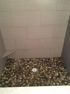 Wood look tile on standup shower walls with river rock floor