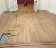 Face nailed white oak flooring with walnut strip border after sanding and hand scraping