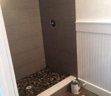 Installed tile shower walls with flat river rock floor