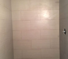 Installed tile shower walls with seat/shelf and flat river rock floor