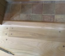 Sanded walnut pegged red oak plank flooring to tile threshold