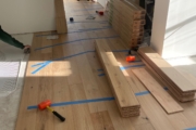 Taping White Oak planks in place while adhesive sets.