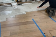 Taping White Oak planks in place while adhesive sets.