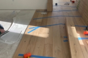 Taping White Oak planks in place while adhesive sets.